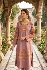 Pakistani model posing in a historic palace garden wearing a dusty mauve Kashmiri floral embroidered phiran kurta.