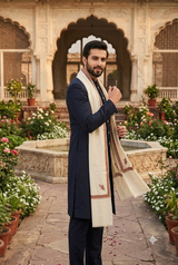 Elegant portrait of a bearded model draping a fine wool Kashmiri men's shawl across the chest in a heritage courtyard.