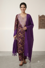 A woman modeling a traditional Indian salwar kameez suit in purple and brown, featuring an embroidered kurta, matching trousers, and a draped dupatta, set against a neutral indoor background.