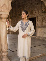 Pakistani model posing in a historic palace wearing an ivory Kashmiri embroidered phiran kurta with grey Aari work