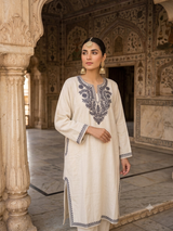Pakistani model posing in a historic palace wearing an ivory Kashmiri embroidered phiran kurta with grey aari work