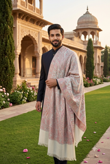 Handsome bearded Pakistani groom in black sherwani wearing a dusty rose and ivory Kashmiri Jamawar shawl in a royal palace garden.