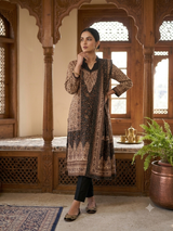 A woman models a traditional long kurta in a brown and beige patterned print, paired with black pants, standing in an ornate wooden architectural interior.
