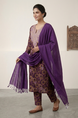 A woman models a traditional Indian outfit consisting of a purple and brown patterned kurta and trousers with a matching purple dupatta, set against a neutral indoor background.