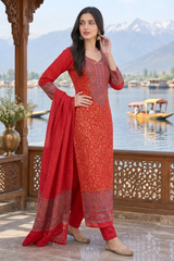 A woman models a red ethnic salwar kameez suit with intricate gold embroidery and a matching red dupatta, set against a scenic lake and mountain background.