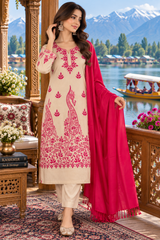 A woman models a traditional South Asian salwar kameez suit set. The set features a beige kurta with vibrant pink floral and peacock embroidery, matching beige trousers, and a bright pink dupatta.