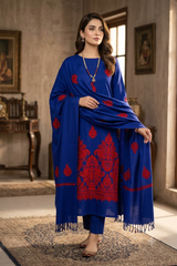 A woman models a royal blue three-piece traditional outfit with red floral embroidery, consisting of a kurta, trousers, and a matching dupatta, set against an elegant indoor background.